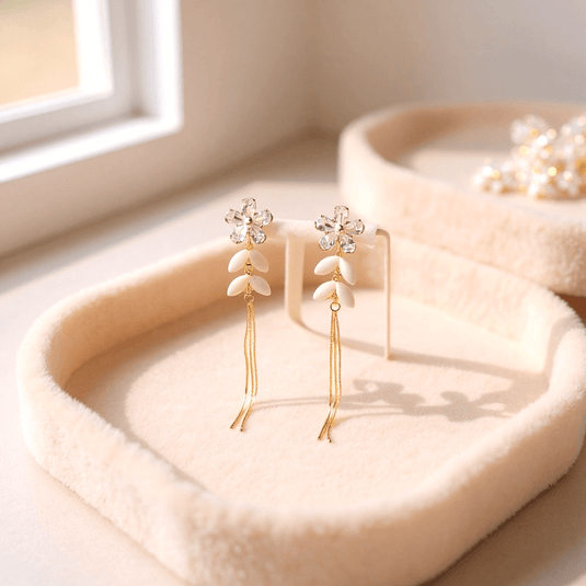 Gold earrings with floral designs on a soft pink surface