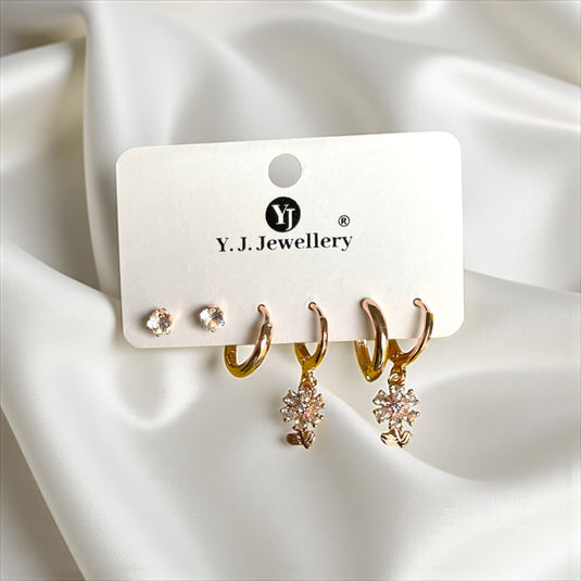 Gold earrings on a Y.J. Jewellery card with white satin background
