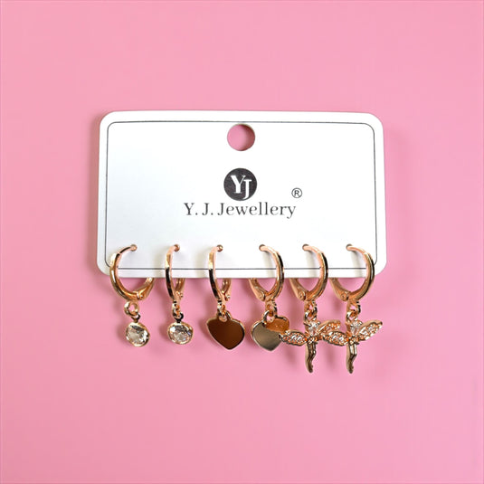 Set of gold earrings with various charms on a Y.J. Jewellery card against a pink background