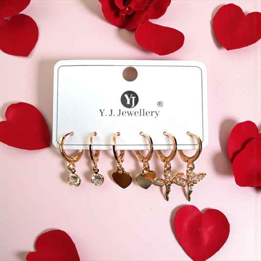Set of gold earrings on a Y.J. Jewellery card with red heart-shaped petals on a pink background