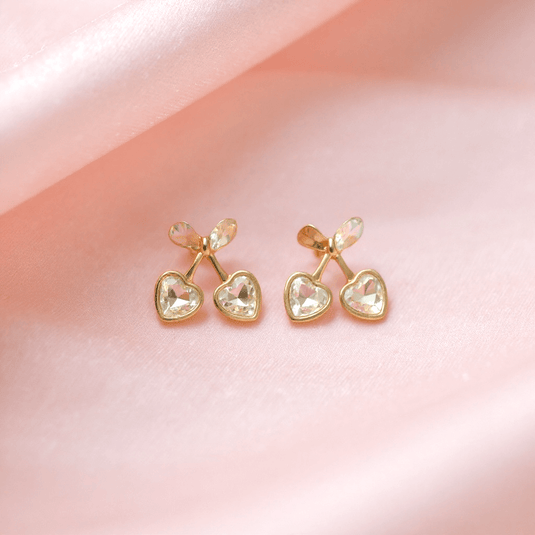 Pair of gold heart-shaped earrings on a pink background