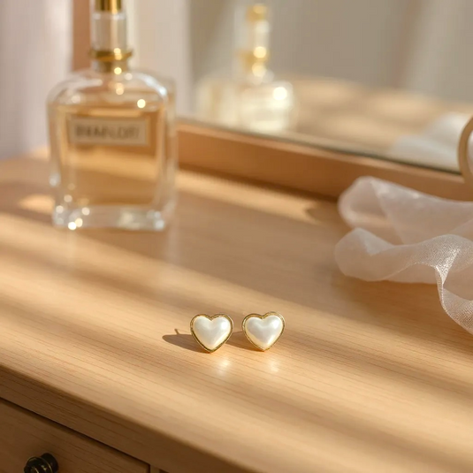 Heart-shaped earrings on a wooden surface with a perfume bottle in the background
