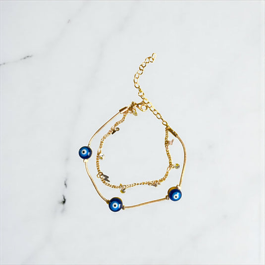 Gold bracelet with blue evil eye charms on a marble surface