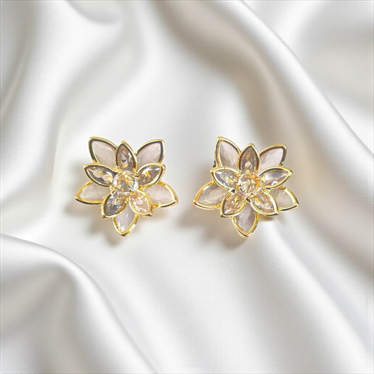 Pair of gold and crystal flower-shaped earrings on a satin surface