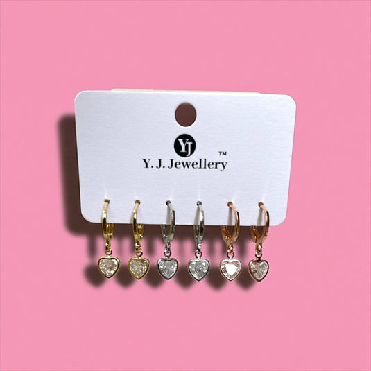 Set of heart-shaped earrings on a Y.J. Jewellery card against a pink background