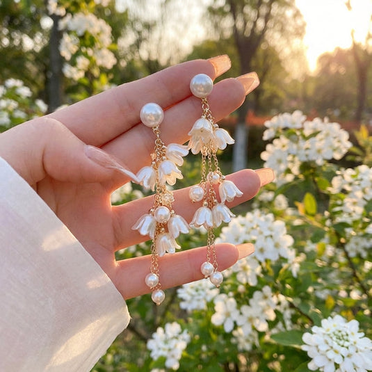 Hand holding a pair of floral earrings with a blurred floral background